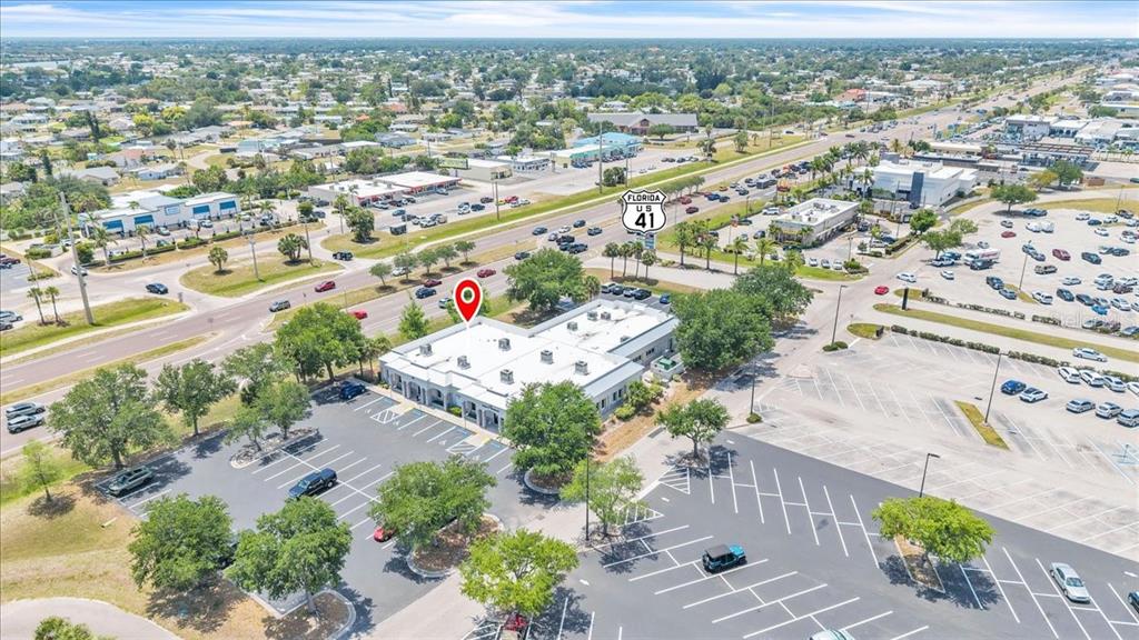 An aerial view shows a commercial building with a parking lot near a highway — 3300 TAMIAMI TRAIL UNIT 102 B, PORT CHARLOTTE, FL