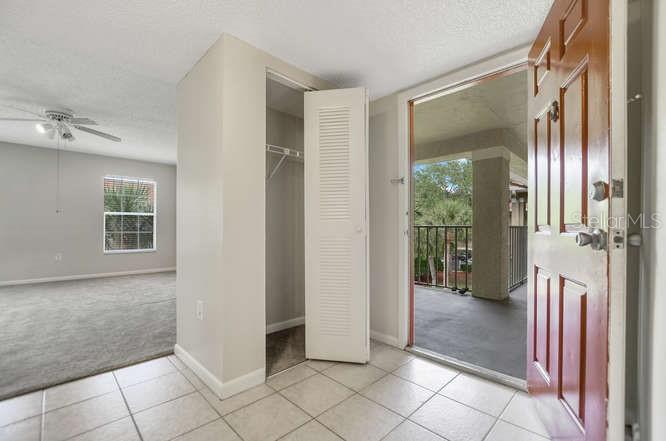An entryway with tile flooring leads to a carpeted living area, a closet, and a balcony — 2690 CORAL LANDINGS BOULEVARD UNIT 438, PALM HARBOR, FL