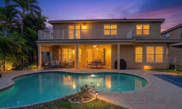 A two-story house with a balcony, covered patio, and a swimming pool at dusk — 11772 Bayou Lane, Boca Raton FL 33498, BOCA RATON, FL