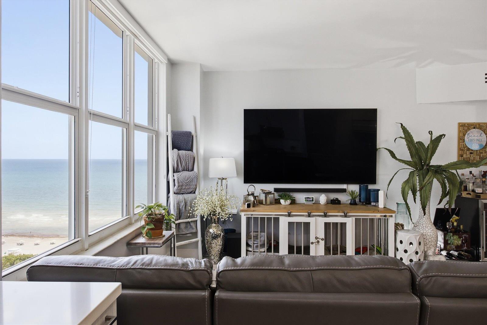 A living room features a large television, a dog crate console, and ocean views — 4747 Collins Avenue # 1109, Miami Beach FL 33140, MIAMI BEACH, FL