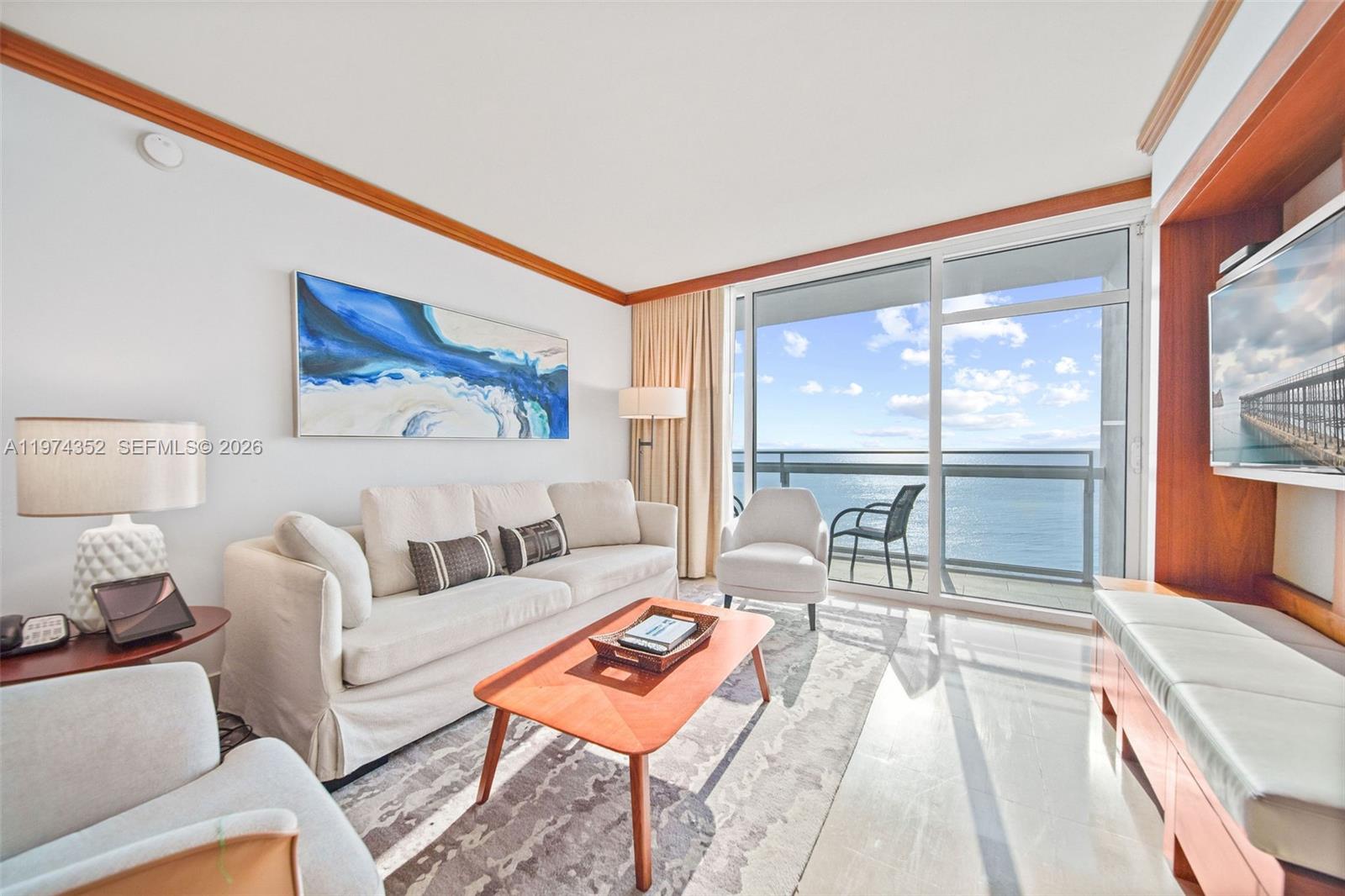 A living room features a sofa, armchairs, coffee table, and a balcony with ocean views — 6801 Collins Ave # 604, Miami Beach FL 33141, MIAMI BEACH, FL