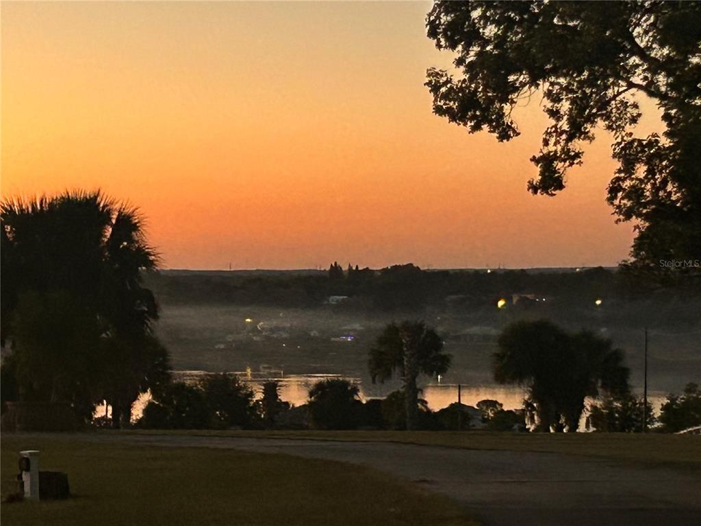 A sunset view over a lake with palm trees and a grassy foreground — 664 S LAKE STARR BOULEVARD, LAKE WALES, FL