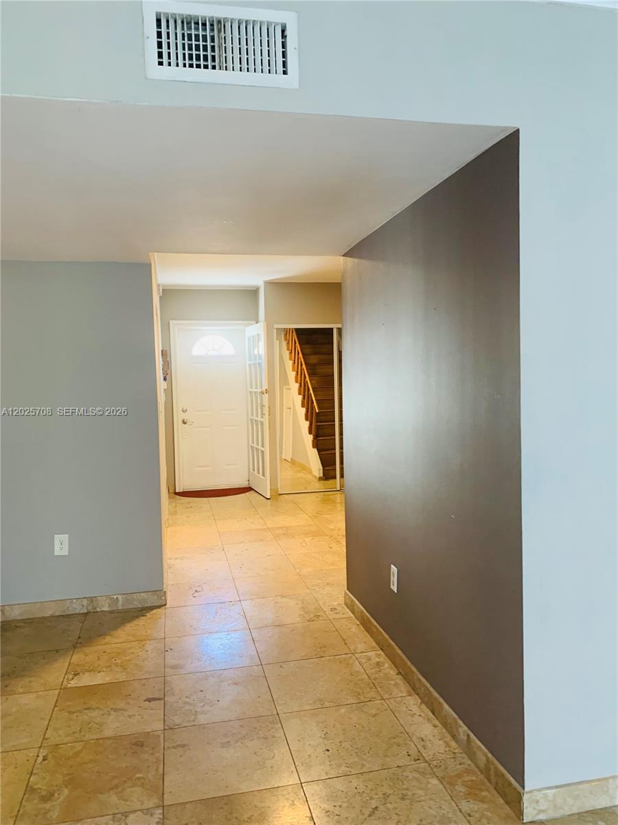 A tiled hallway leads to a front door and a staircase with a mirrored closet — 1651 NE 115th St # 21C, Miami FL 33181, MIAMI, FL