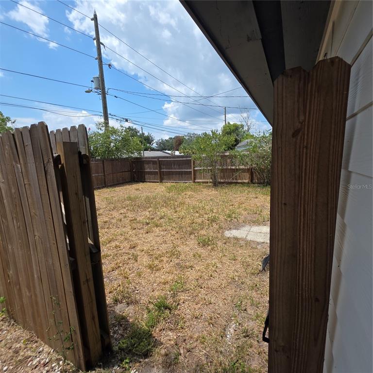 A fenced backyard with dry grass and a utility pole under a cloudy sky — 5101 ORANGE AVENUE N UNIT B, WINTER PARK, FL