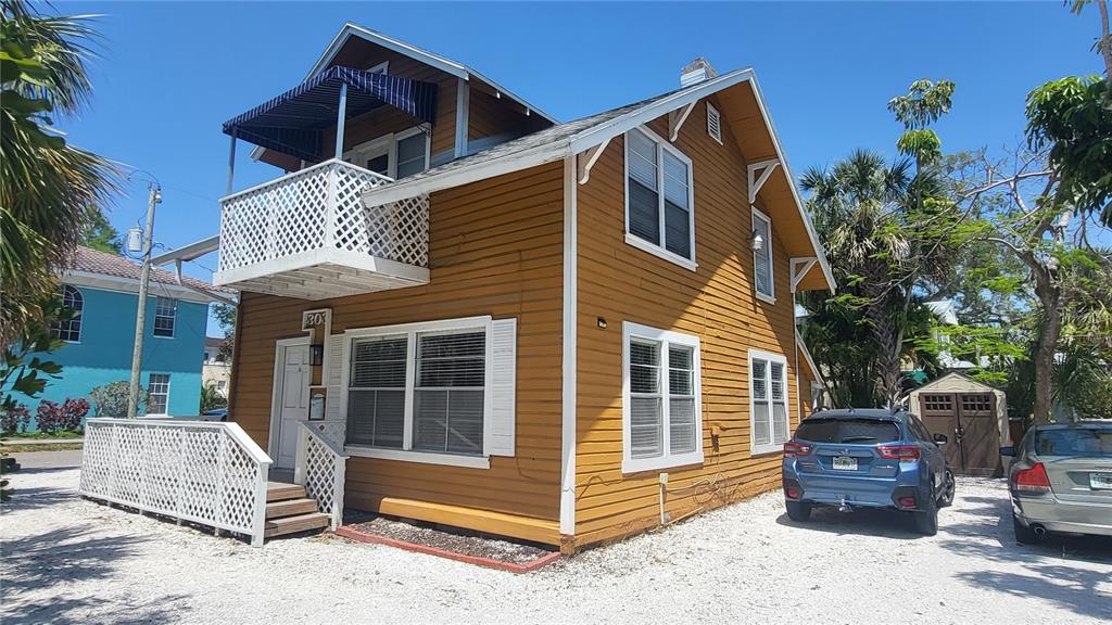 A two-story yellow house with a white balcony and a gravel driveway — 301 S OSPREY AVENUE, SARASOTA, FL
