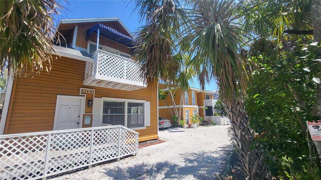 A two-story yellow building with a white balcony and a gravel parking area — 301 S OSPREY AVENUE, SARASOTA, FL