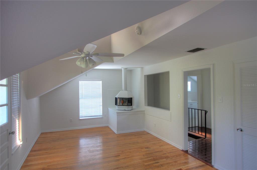 An empty room with hardwood floors, a white fireplace, and a vaulted ceiling — 301 S OSPREY AVENUE, SARASOTA, FL