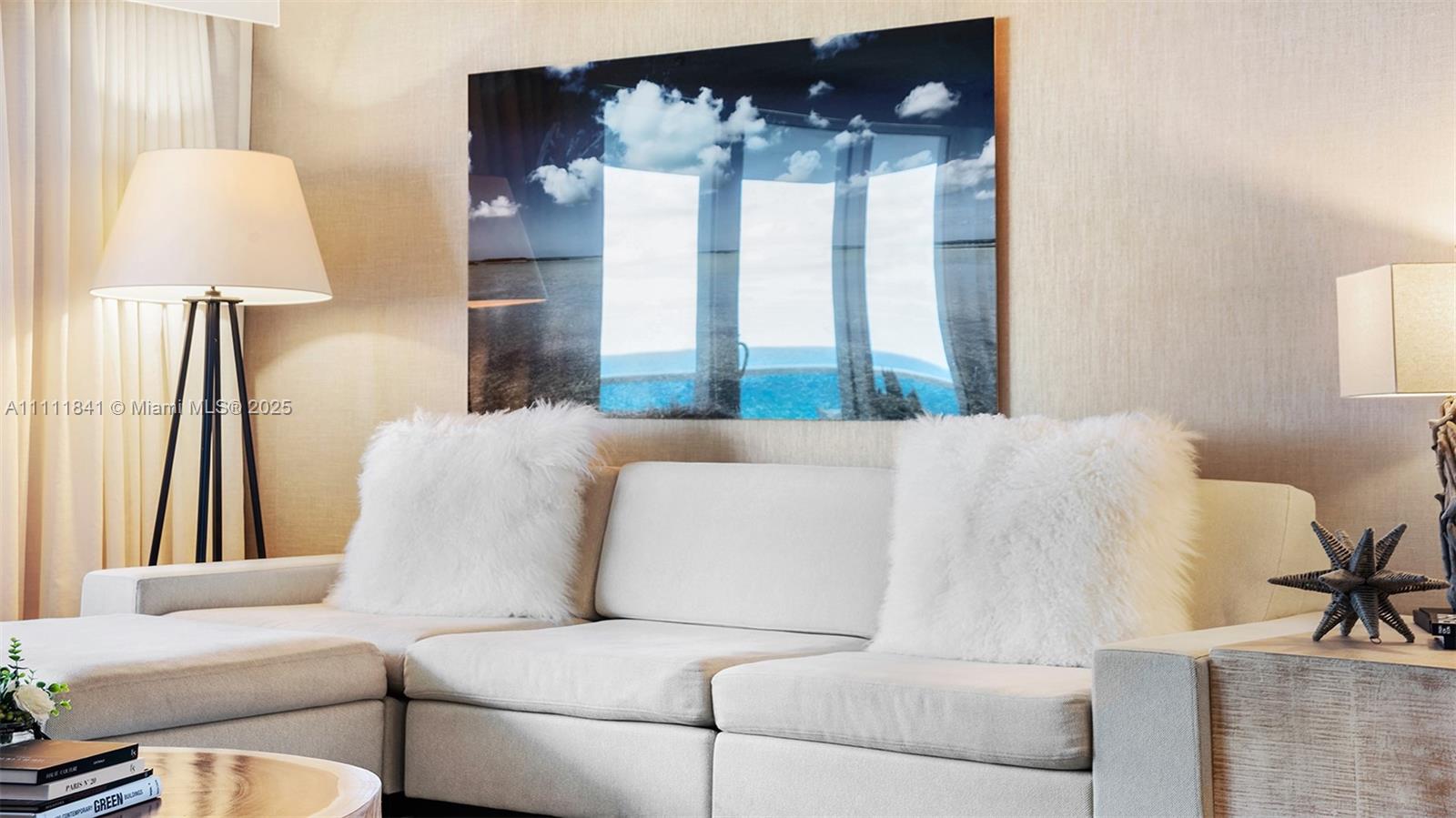 A living room features a white sofa with fluffy pillows, a floor lamp, and wall art — 102 24th St # 904, Miami Beach FL 33139, MIAMI BEACH, FL