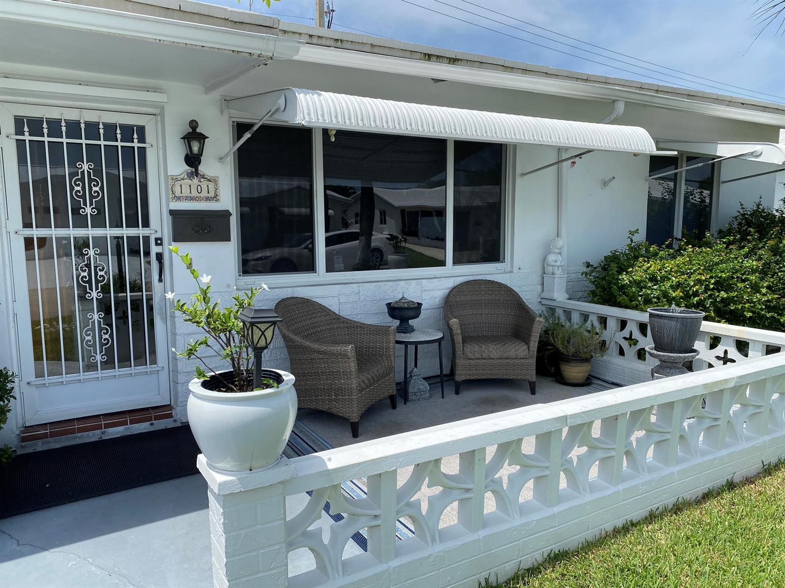 A white house exterior features a front patio with wicker chairs and decorative block walls — 1101 Leisure Lane, Boynton Beach FL 33426, BOYNTON BEACH, FL