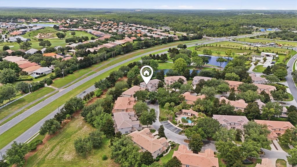 An aerial view shows a residential community with multi-story townhomes, green spaces, and a road — 1668 W SPRING MEADOW LOOP, LECANTO, FL