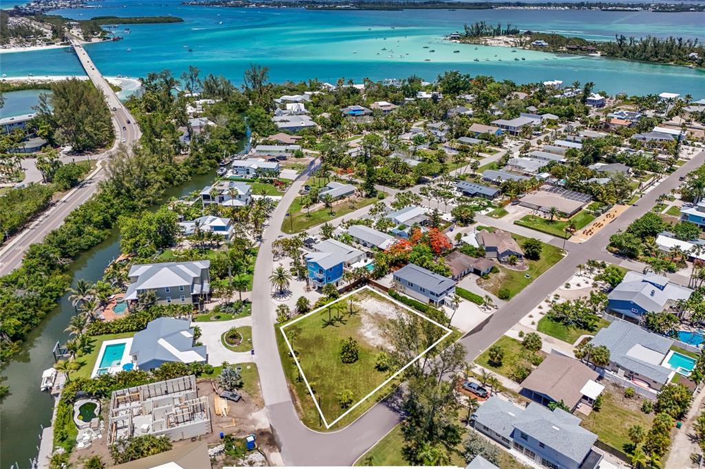 An aerial view shows a vacant, grass-covered residential lot outlined in white within a coastal neighborhood — 591 RUSSELL STREET, LONGBOAT KEY, FL
