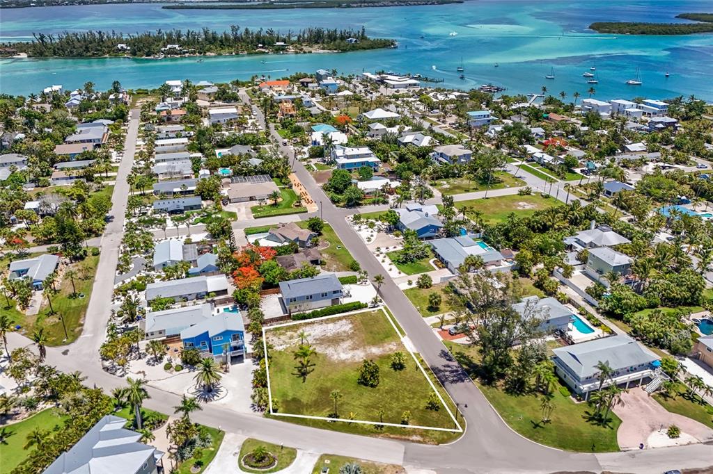 An aerial view shows a vacant, grass-covered residential lot outlined in white within a coastal neighborhood — 591 RUSSELL STREET, LONGBOAT KEY, FL