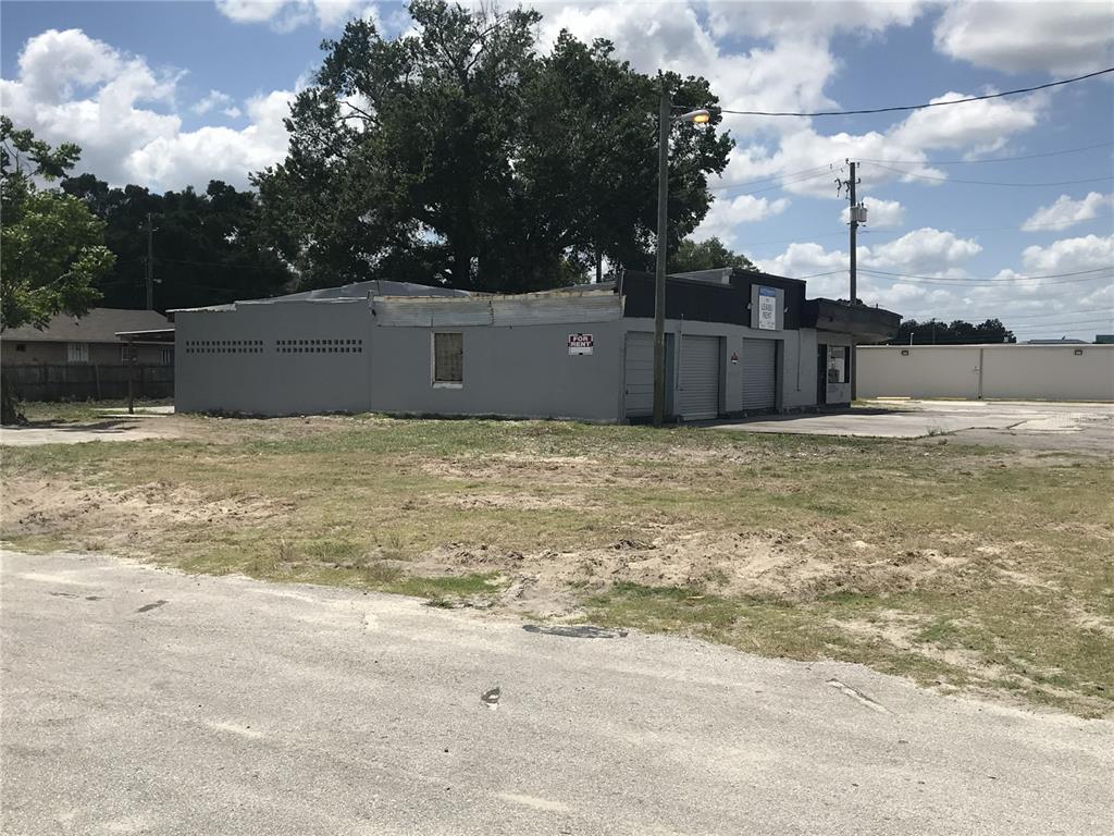 A gray commercial building with roll-up doors sits on a lot with sparse grass — 204 SNIVELY AVENUE, ELOISE, FL