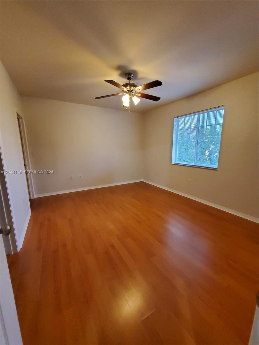 An empty bedroom features light-colored walls, a ceiling fan, and hardwood flooring — 6458 Emerald Dunes # 304, West Palm Beach FL 33411, WEST PALM BEACH, FL