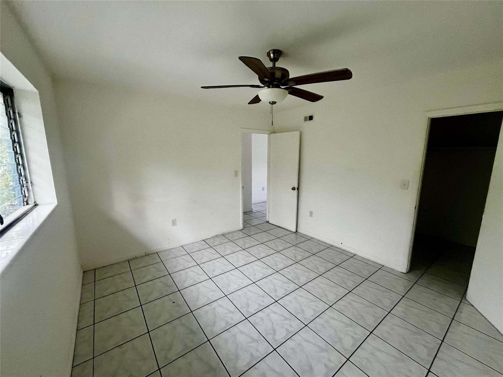 An empty room with white walls, a ceiling fan, and light-colored square floor tiles — 751 NE 83rd Terrace # 18, Miami FL 33138, MIAMI, FL