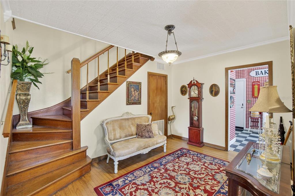 An entryway features a wooden staircase, a vintage settee, a grandfather clock, and a patterned rug — 2203 HIDDEN POND ROAD, PLANT CITY, FL