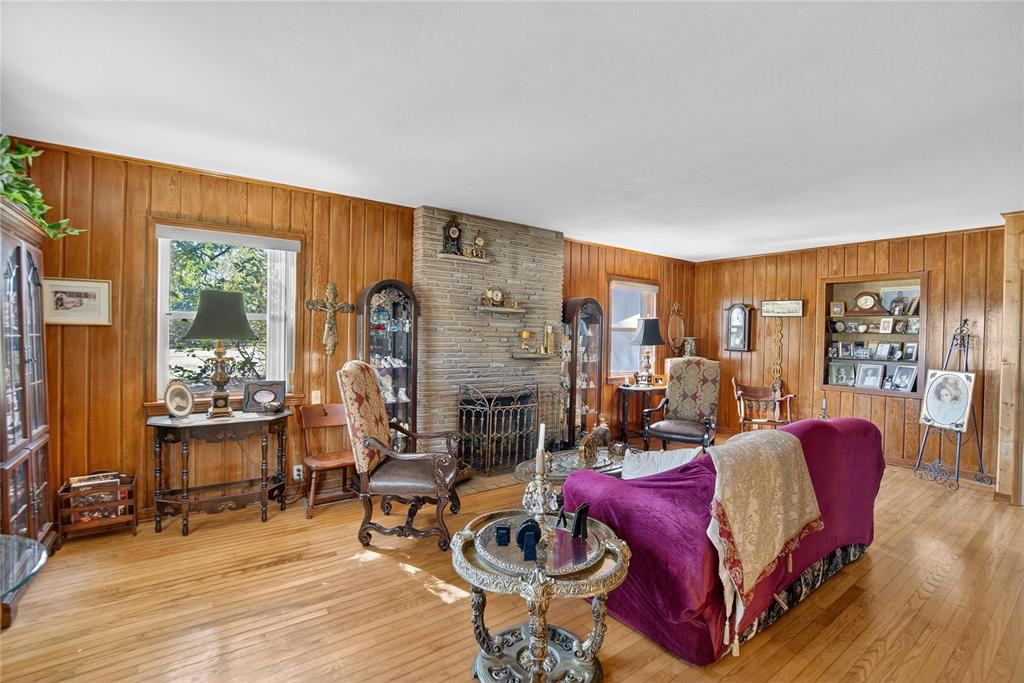 A living room features wood-paneled walls, a stone fireplace, and hardwood flooring — 2203 HIDDEN POND ROAD, PLANT CITY, FL