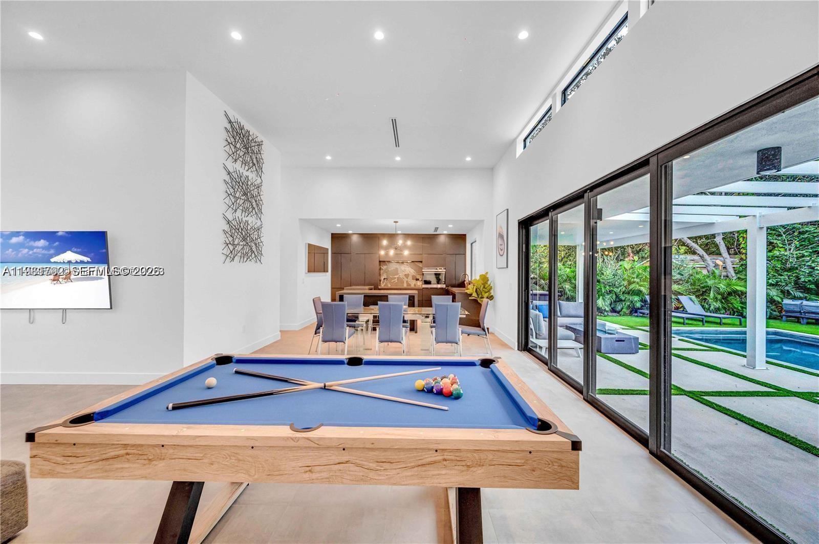 A modern game room features a pool table, dining area, and large sliding glass doors — 155 NW 51st St # 0, Miami FL 33127, MIAMI, FL