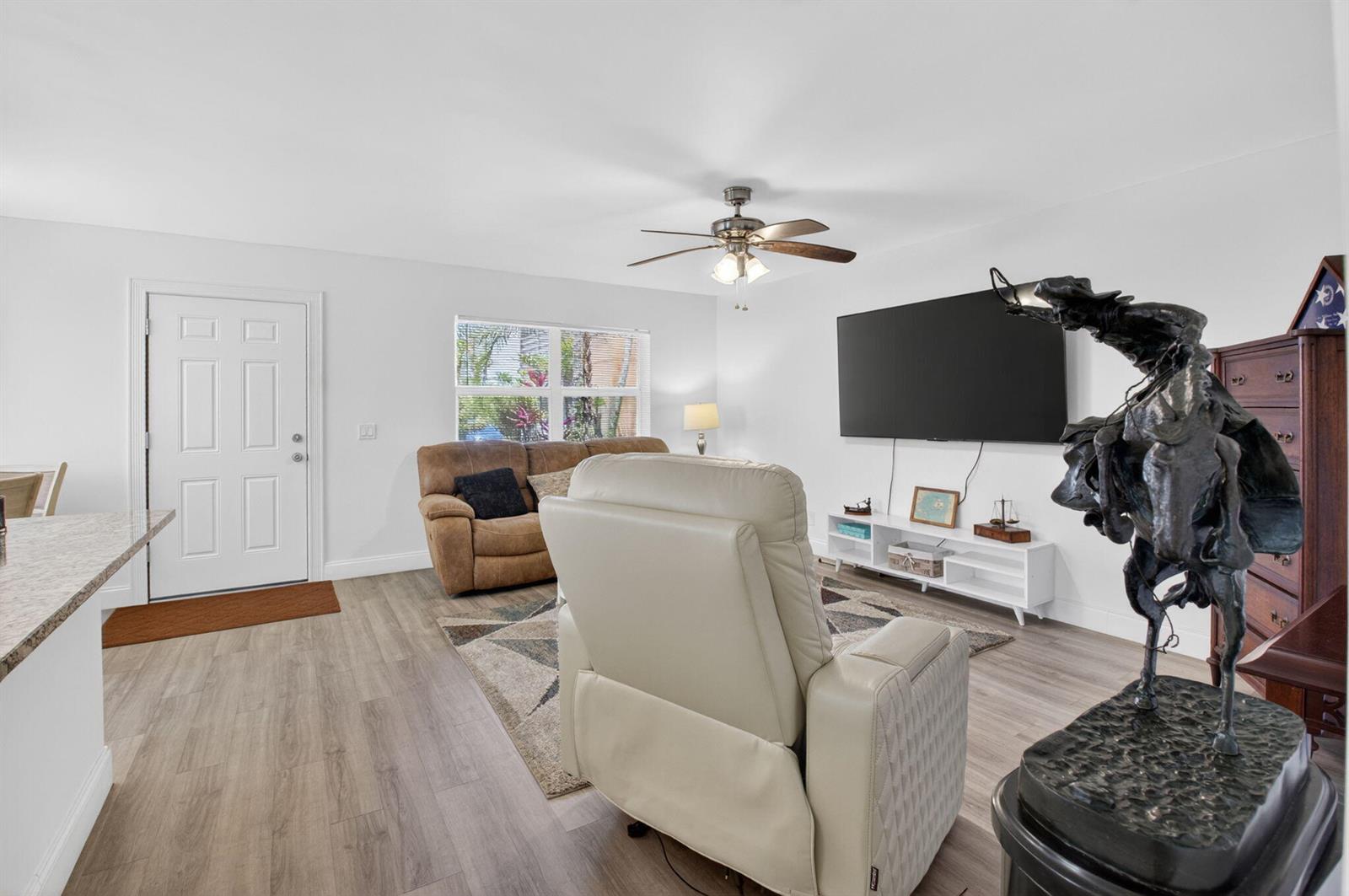 A living room features a white recliner, a brown sofa, a television, and a statue — 14 Flanders # A, Delray Beach FL 33484, DELRAY BEACH, FL