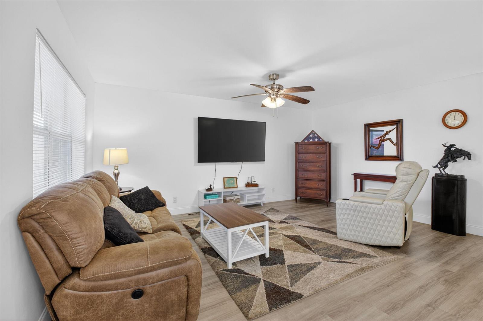 A living room features a brown sofa, white recliner, television, and a geometric area rug — 14 Flanders # A, Delray Beach FL 33484, DELRAY BEACH, FL