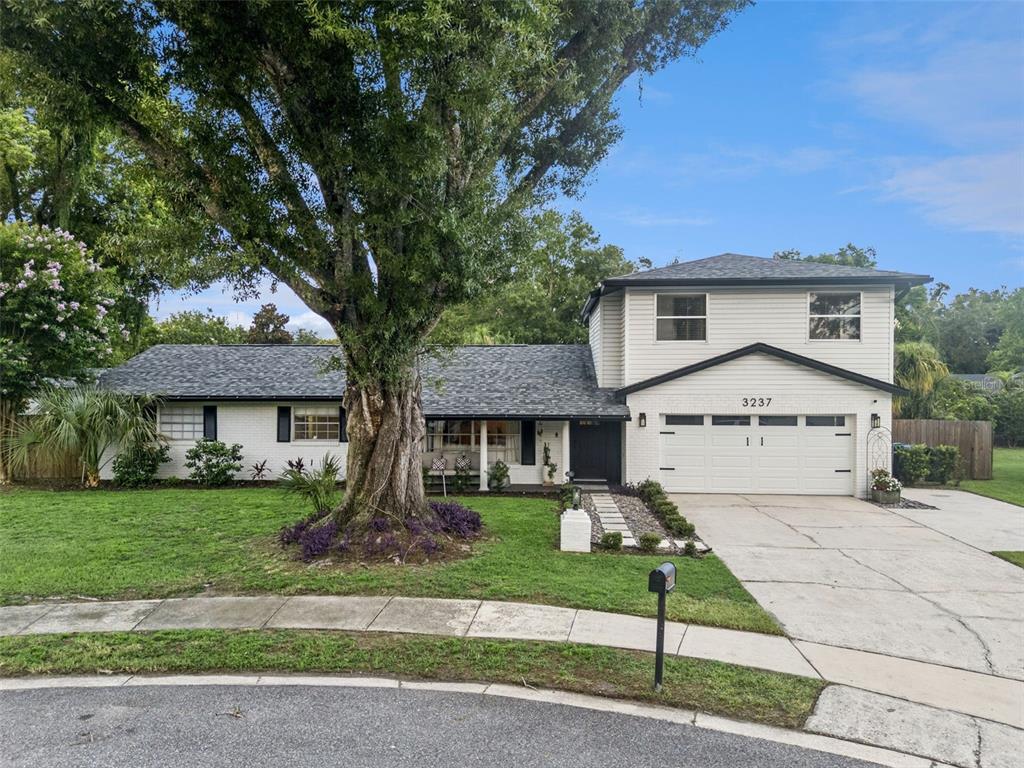 A two-story house with white siding and brick, a large tree, and a concrete driveway — 3237 KEW GARDENS LANE, ORLANDO, FL