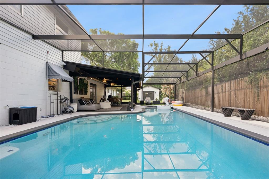 A rectangular swimming pool sits inside a screened-in patio area next to a house — 3237 KEW GARDENS LANE, ORLANDO, FL