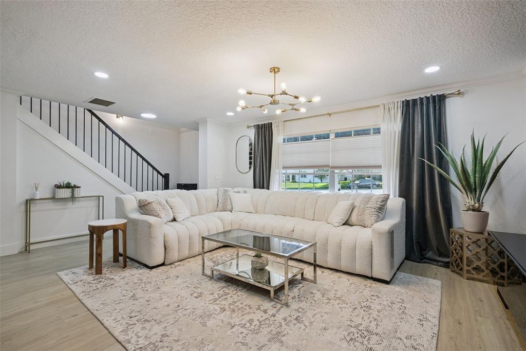 A modern living room features a white sectional sofa, a glass coffee table, and stairs — 3237 KEW GARDENS LANE, ORLANDO, FL
