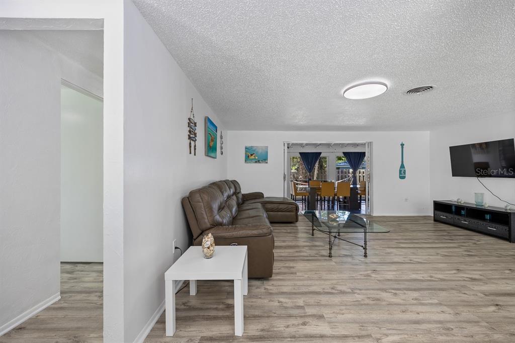 A living room with wood-look flooring, a brown sectional sofa, and a glass coffee table — 4055 BAY OAKS CIRCLE, ENGLEWOOD, FL