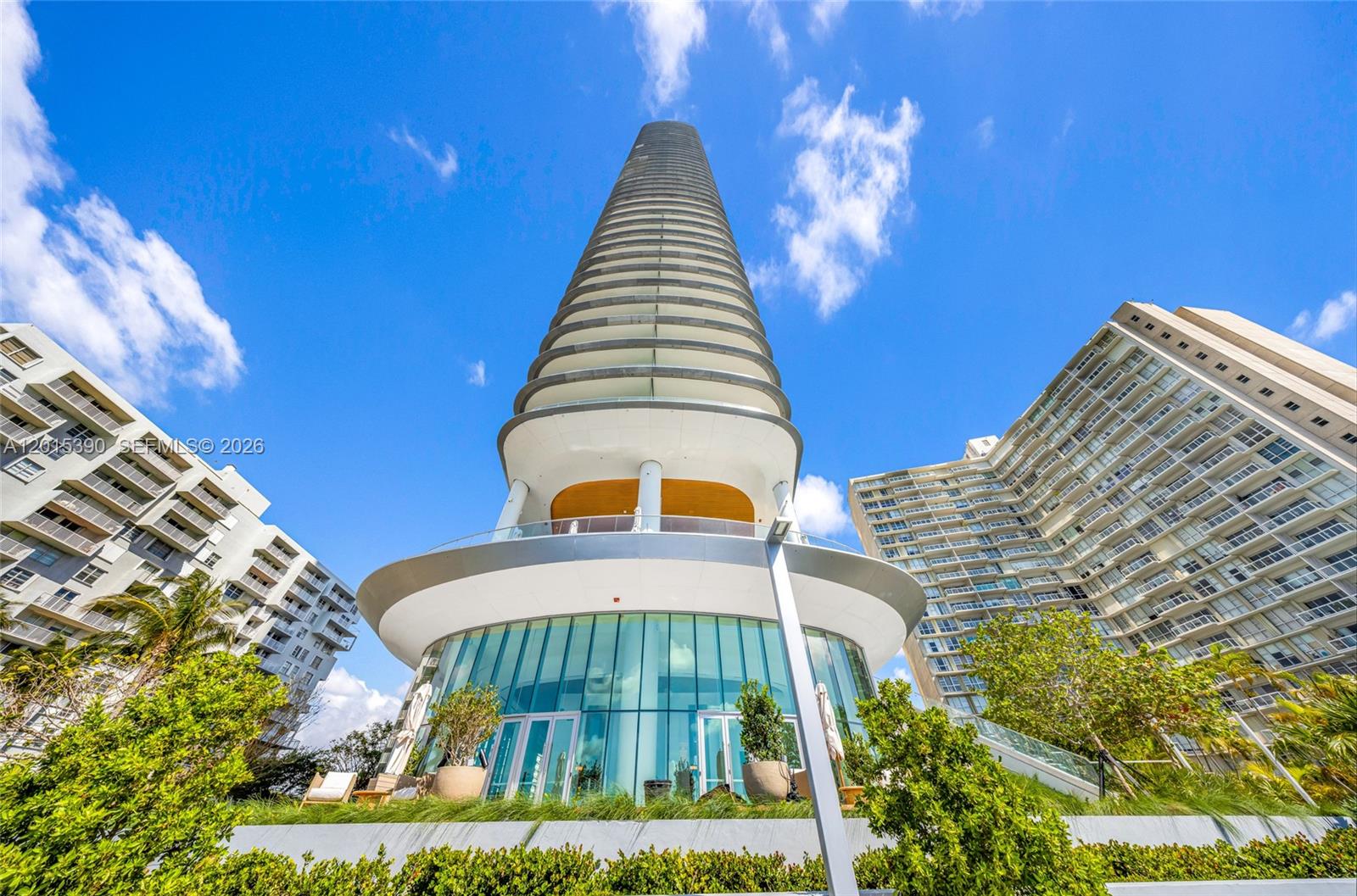 A low-angle view shows a modern, cylindrical high-rise tower surrounded by other residential buildings — 175 SE 25 Road # 1203, Miami FL 33129, MIAMI, FL