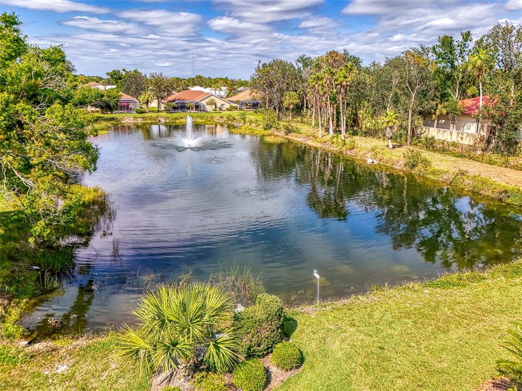 An aerial view of a pond with a fountain surrounded by houses and lush trees — 107 WAYFOREST DRIVE, VENICE, FL