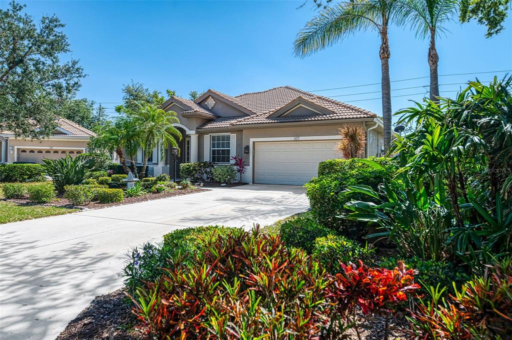 A single-story house with a beige stucco exterior, tile roof, and a two-car garage — 107 WAYFOREST DRIVE, VENICE, FL