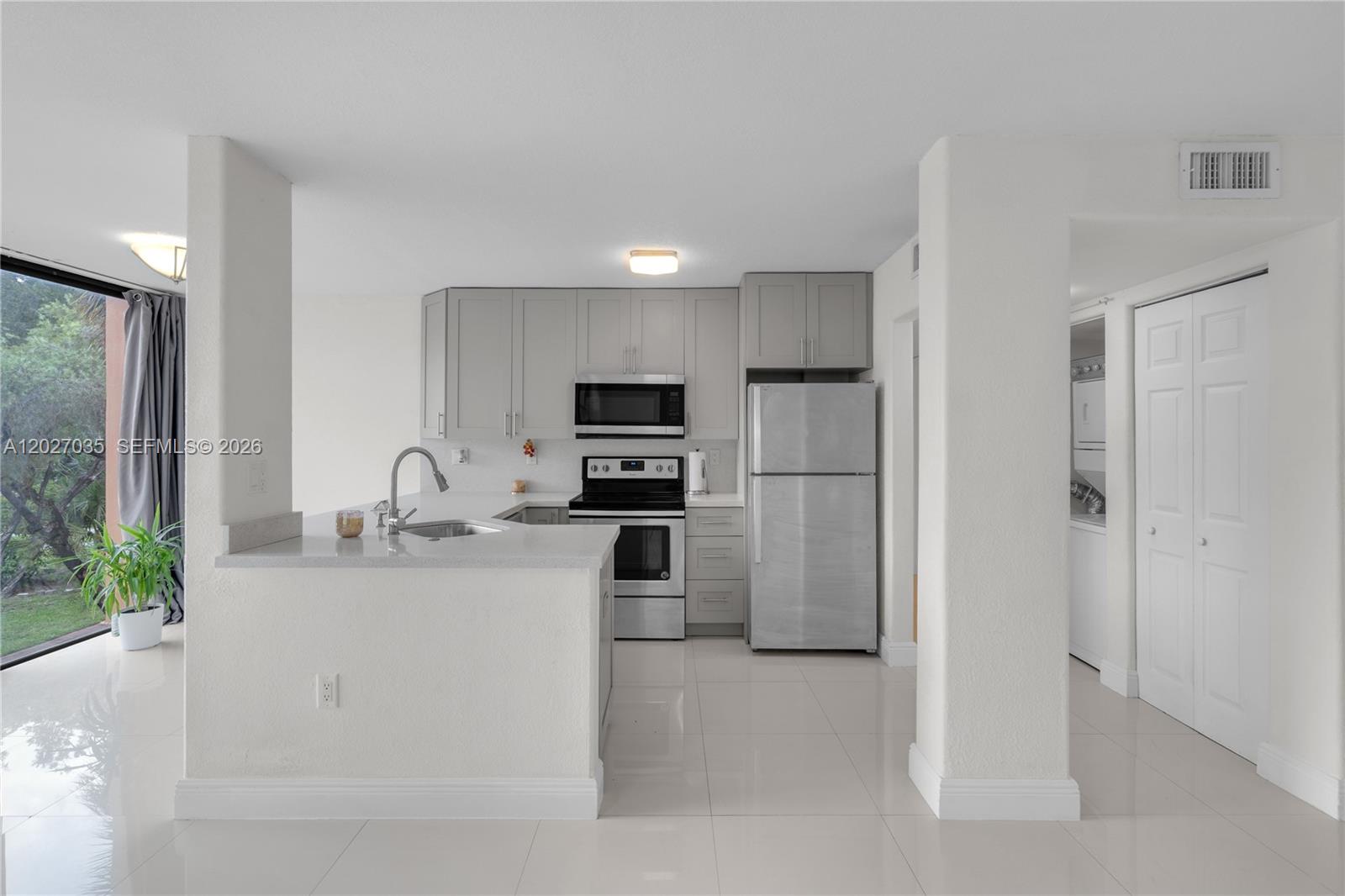 A kitchen features gray cabinets, stainless steel appliances, and a peninsula counter with a sink — 9440 W Flagler St # 208, Miami FL 33174, MIAMI, FL