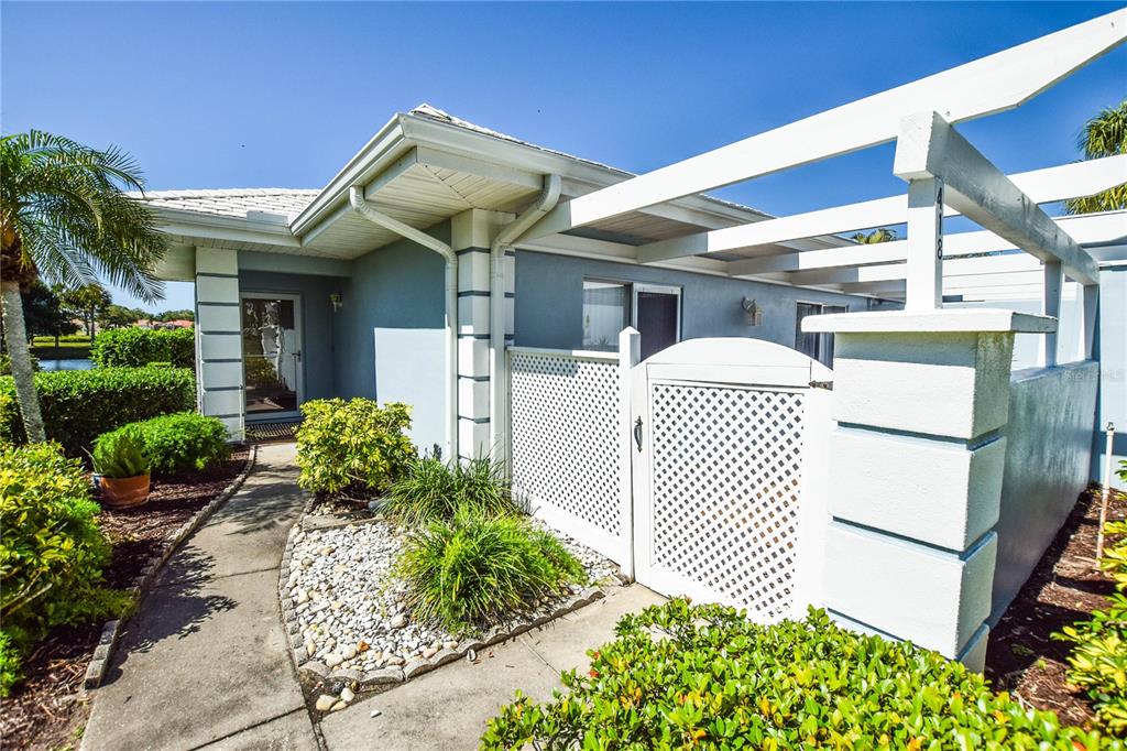 A light blue house exterior features a white lattice gate and a wooden pergola — 418 WEXFORD CIRCLE UNIT 125, VENICE, FL