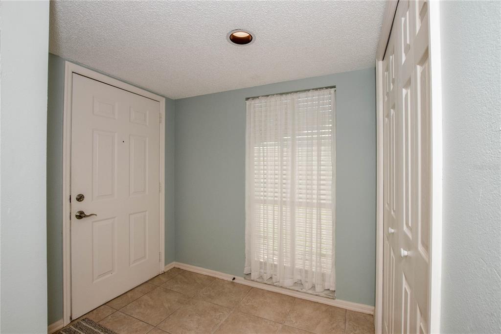 An entryway features light blue walls, tile flooring, a white door, and a closet — 418 WEXFORD CIRCLE UNIT 125, VENICE, FL