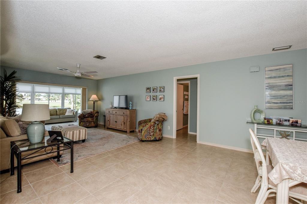 A living room with light blue walls, tile flooring, and a dining area — 418 WEXFORD CIRCLE UNIT 125, VENICE, FL