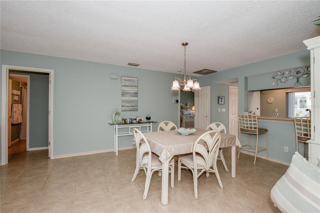 A dining room with a square table, four chairs, a chandelier, and tile flooring — 418 WEXFORD CIRCLE UNIT 125, VENICE, FL