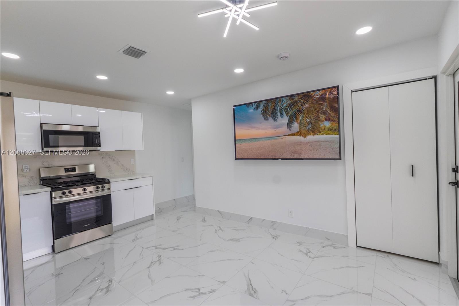 A modern kitchen features white cabinets, stainless steel appliances, and white marble-patterned tile flooring — 3001 SW 35th Ave, West Park FL 33023, WEST PARK, FL