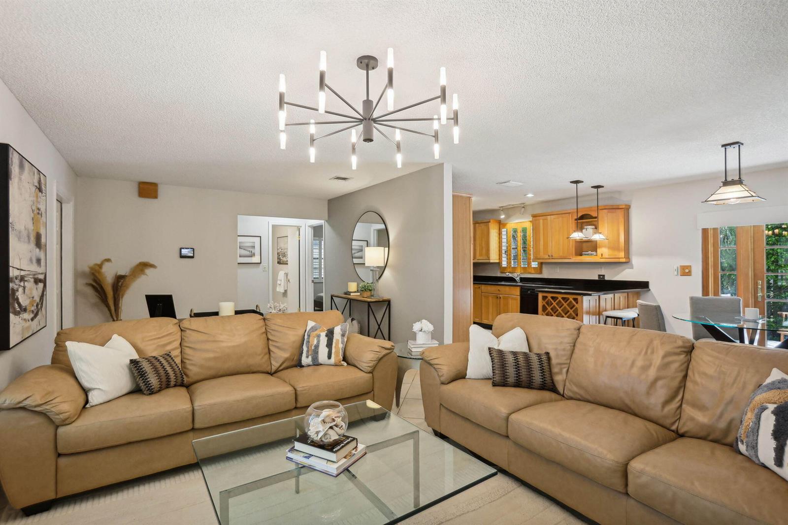 A living room with two tan leather sofas, a glass coffee table, and an open kitchen — 3101 Pierson Drive, Delray Beach FL 33483, DELRAY BEACH, FL