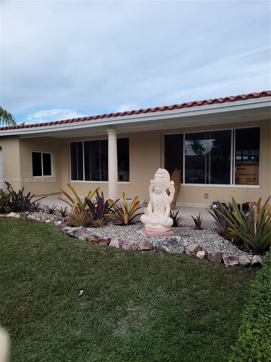 The exterior of a house features a stone-covered garden bed with a central statue — SOUTH MIAMI, FL
