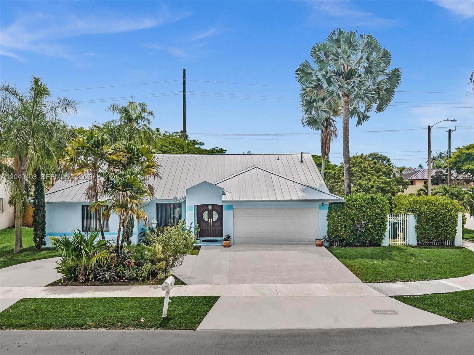 A light blue single-story house features a metal roof, a two-car garage, and palm trees — 16951 SW 147th Ct, Miami FL 33187, MIAMI, FL