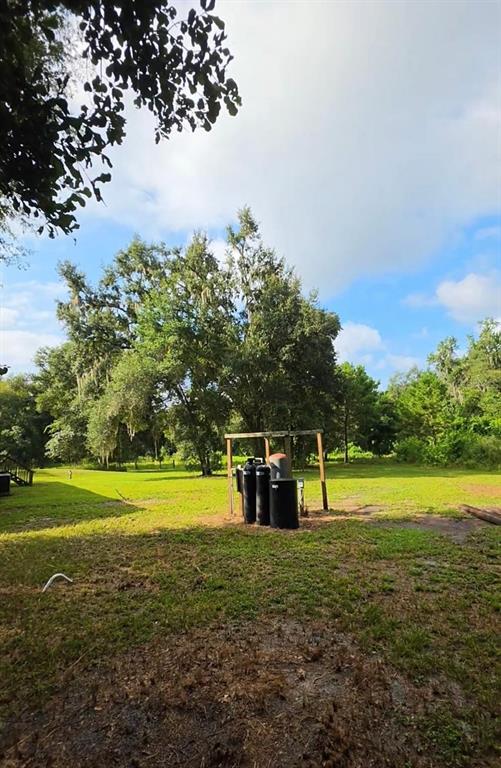 A grassy yard features a wooden frame structure housing several black water treatment tanks — 3415 CR 679, WEBSTER, FL