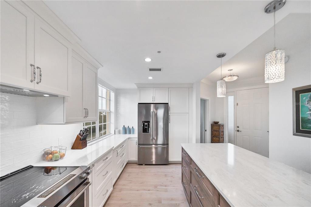 A modern kitchen features white cabinets, stainless steel appliances, and a large central island — 13113 GASPARILLA ROAD UNIT 405, PLACIDA, FL