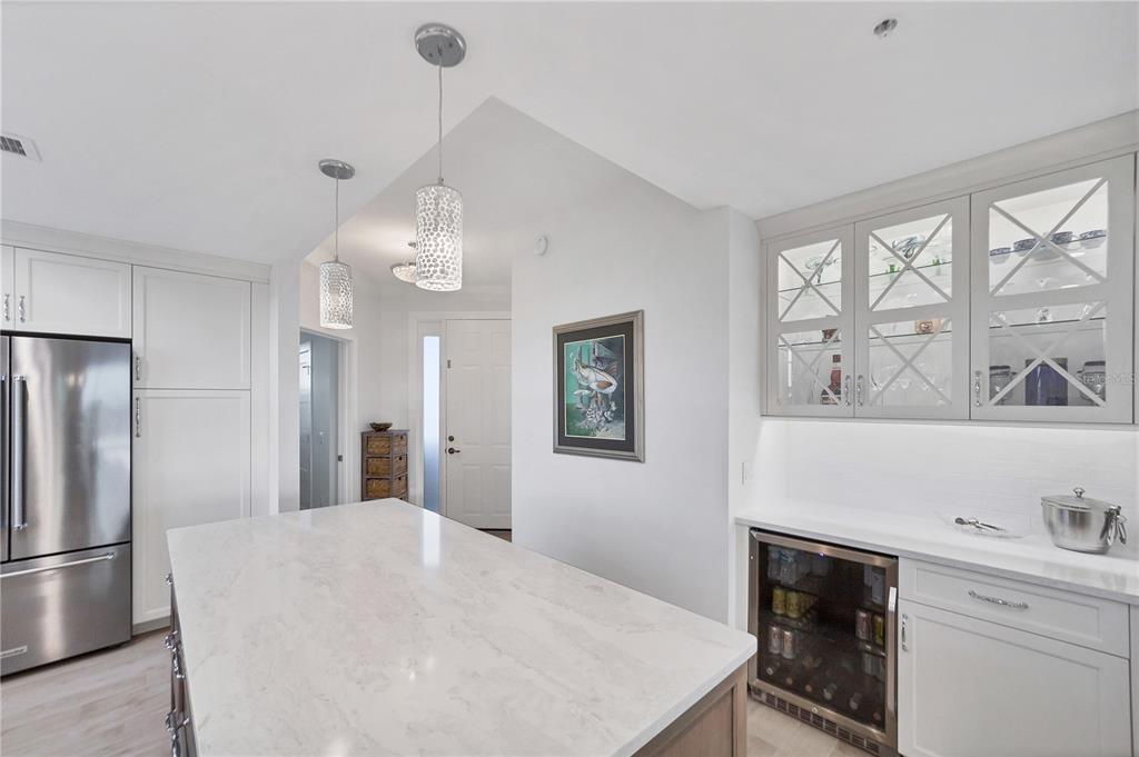 A kitchen with a white marble island, stainless steel refrigerator, and glass-front upper cabinets — 13113 GASPARILLA ROAD UNIT 405, PLACIDA, FL