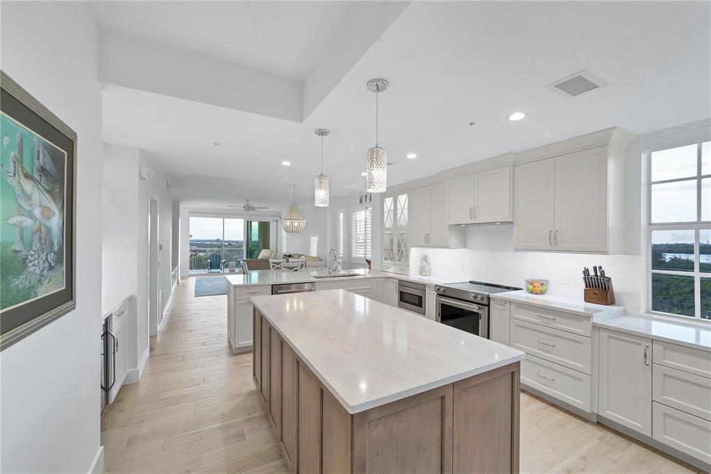 A modern kitchen features a large center island, light wood flooring, and white cabinetry — 13113 GASPARILLA ROAD UNIT 405, PLACIDA, FL