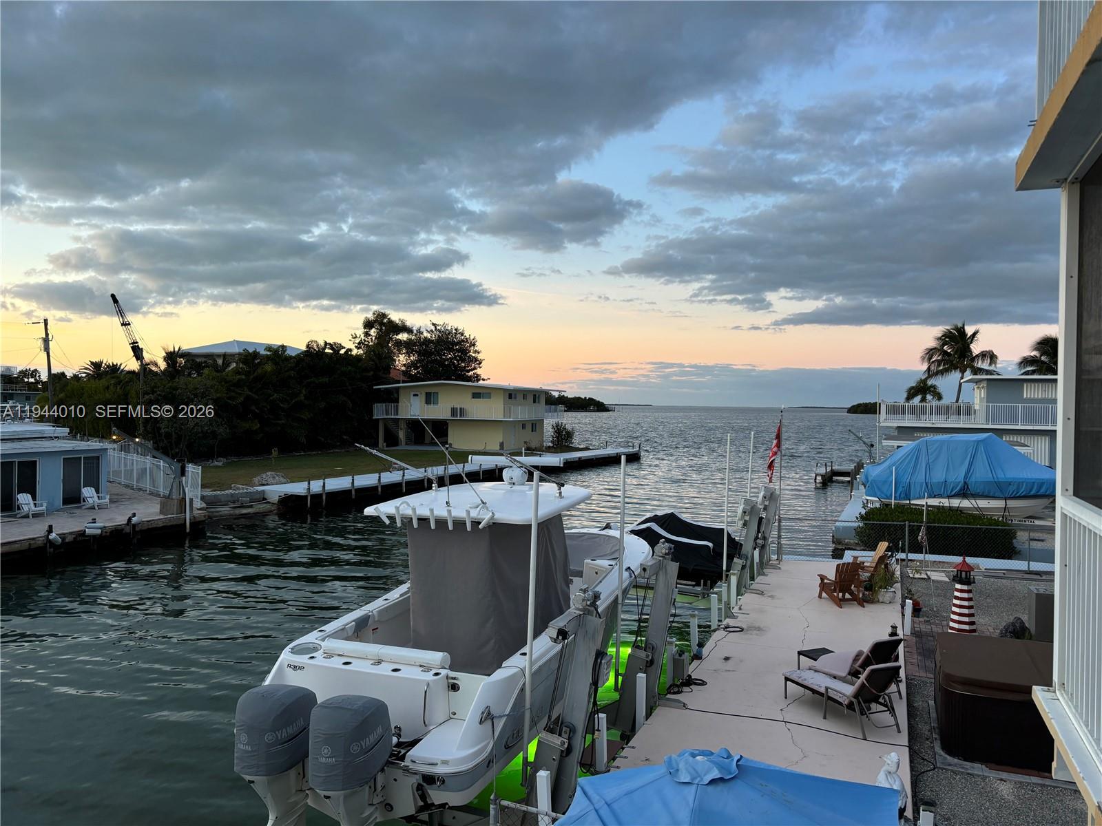 A boat is docked at a waterfront property with a pier and lounge chairs — 235 Anne Bonny Dr, Key Largo FL 33037, KEY LARGO, FL