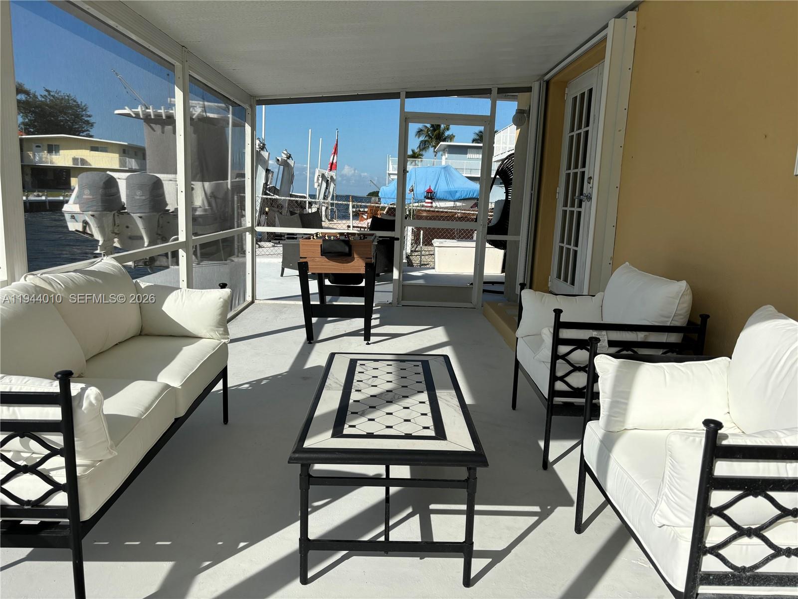 A screened-in patio features white cushioned furniture, a coffee table, and a foosball table — 235 Anne Bonny Dr, Key Largo FL 33037, KEY LARGO, FL
