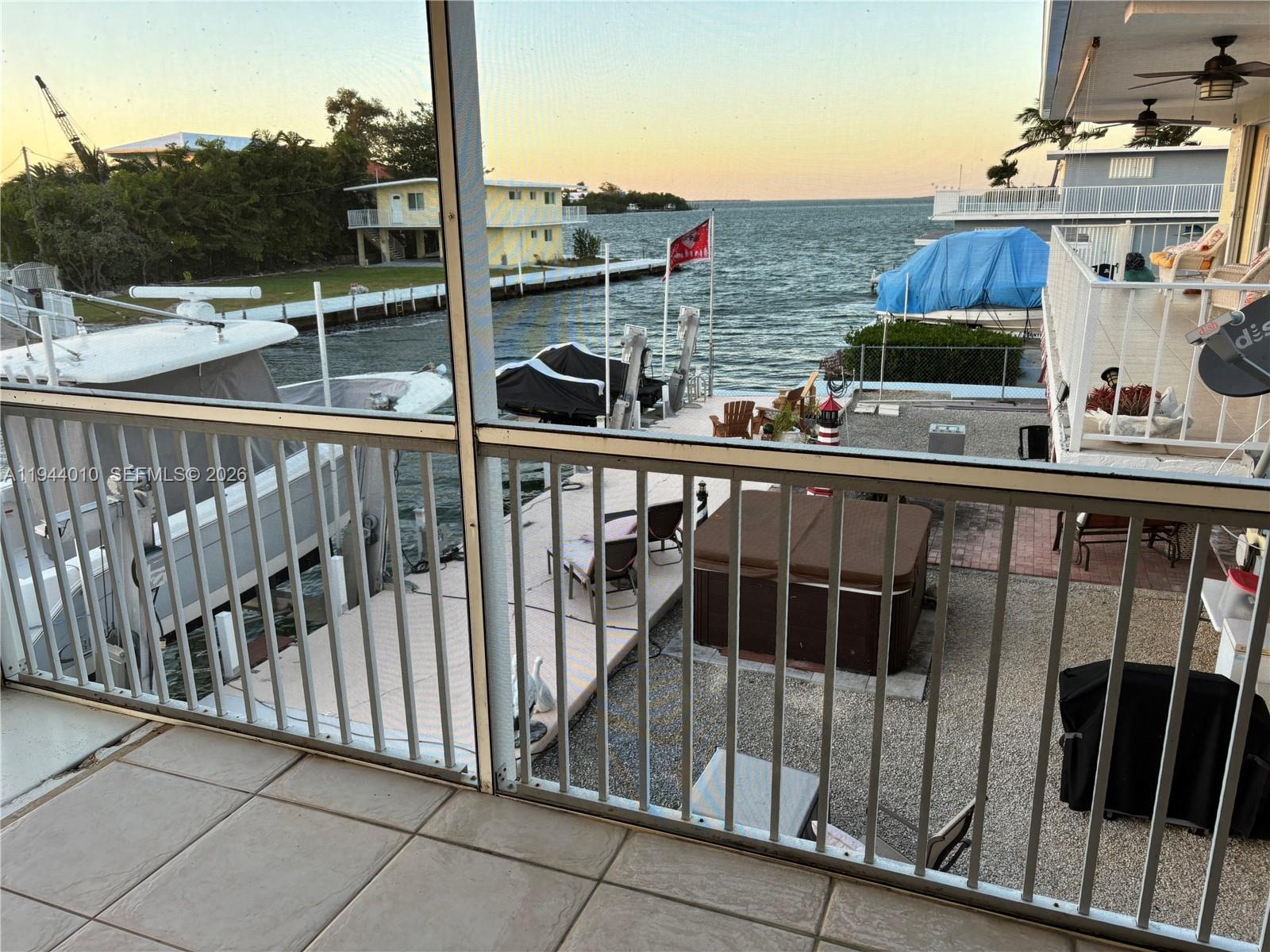 A balcony view overlooks a boat dock, a hot tub, and a waterfront canal — 235 Anne Bonny Dr, Key Largo FL 33037, KEY LARGO, FL