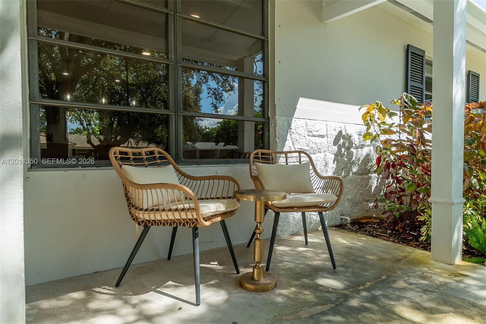 Two wicker chairs and a small gold table sit on a concrete patio — 712 Tradewind Dr, North Palm Beach FL 33408, NORTH PALM BEACH, FL