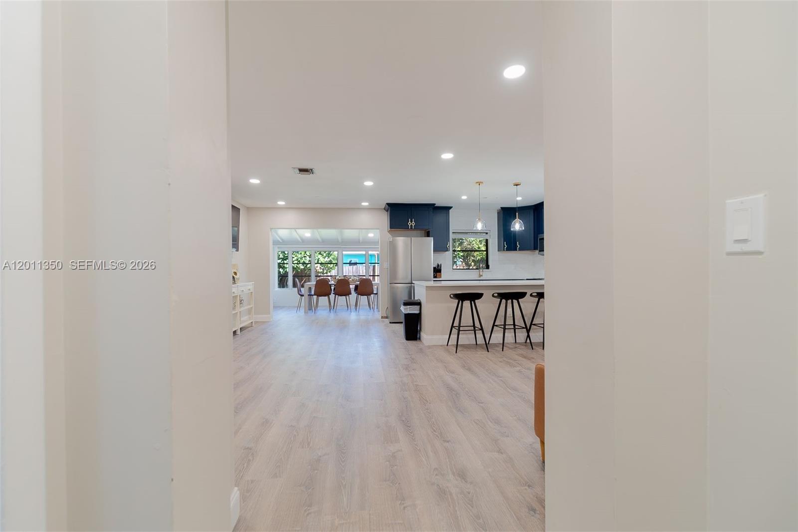 An open-concept kitchen features dark blue cabinets, a breakfast bar, and light wood-look flooring — 712 Tradewind Dr, North Palm Beach FL 33408, NORTH PALM BEACH, FL
