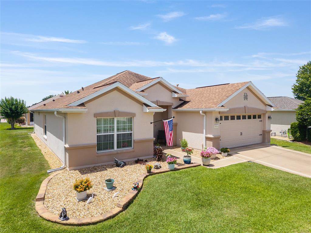 A single-story suburban house with a tan stucco exterior, a two-car garage, and landscaping — 8716 SE 136TH PLACE, SUMMERFIELD, FL